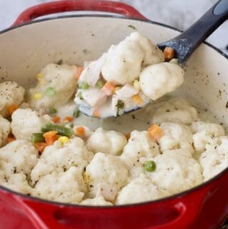 Creamy Chicken and Dumplings being spooned out of a red pot.