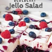 Sliced blueberry jello salad with whipped cream and berries on top.