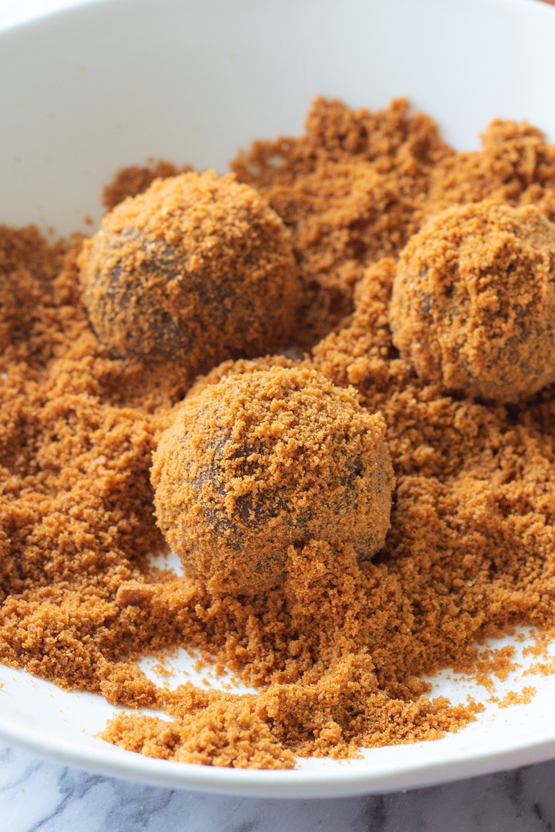 3 balls of raw chocolate cookie butter filled dough in biscoff cookie crumbs.