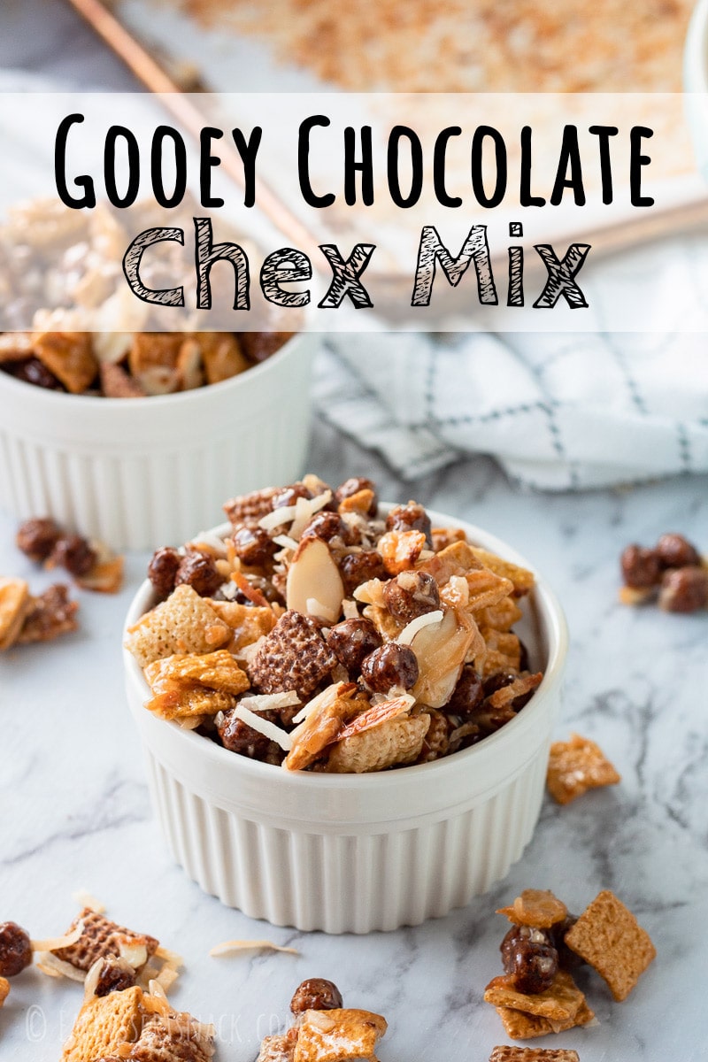 White bowl of chocolate gooey chex mix on marble countertop. 