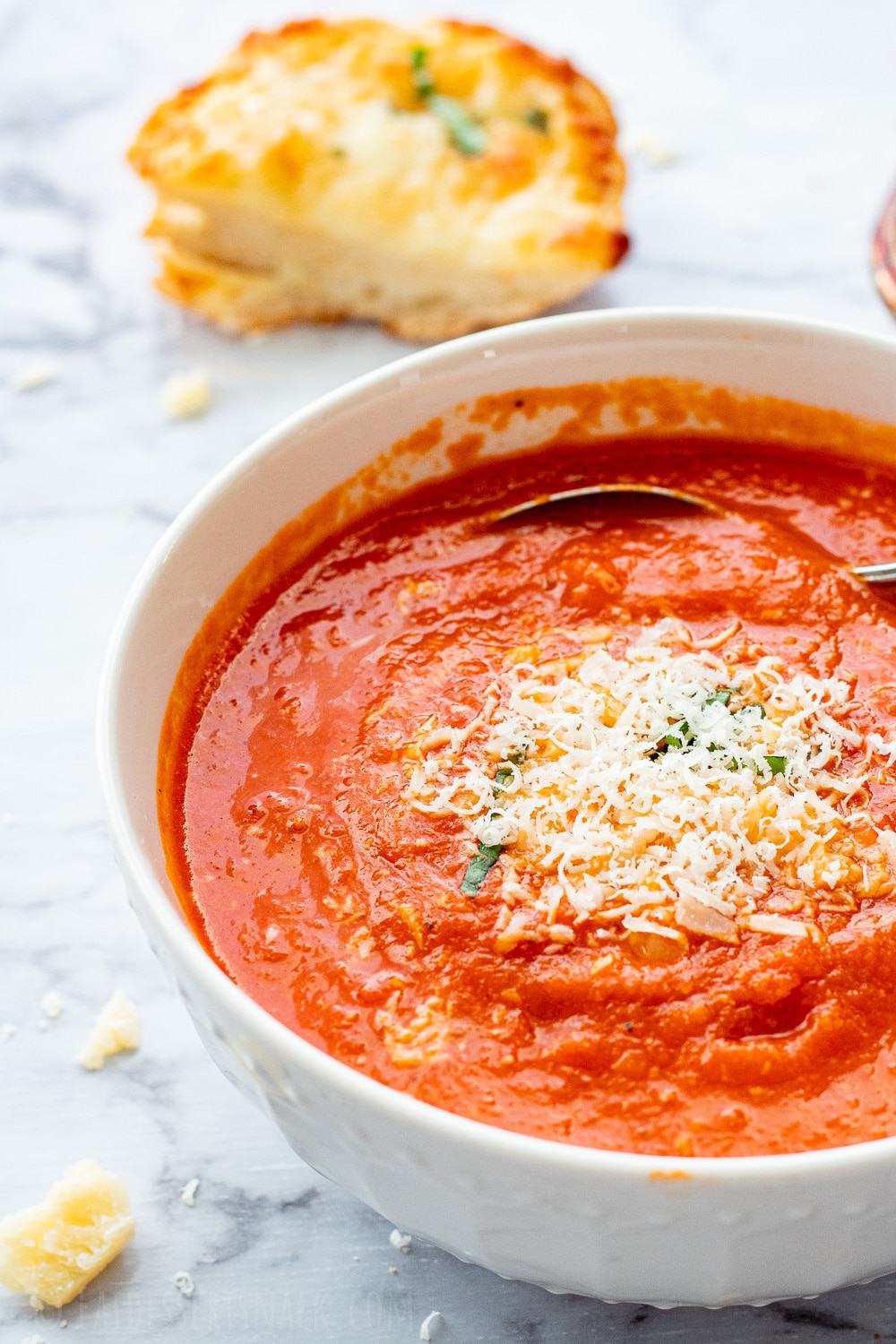 Cooked homemade tomato soup with parmesan cheese in a white bowl. 