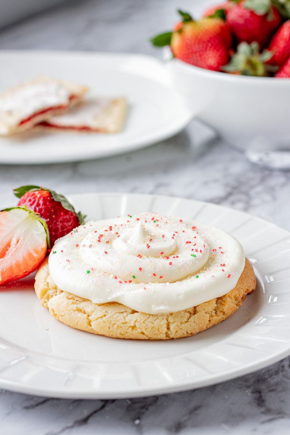 Baked strawberry poptart sugar cookie on a white plate with strawberries.