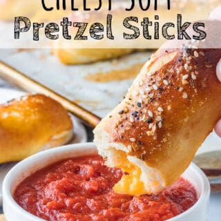 Baked cheese stuffed pretzel over white bowl of pizza sauce.