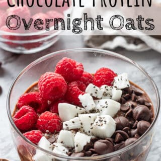 Glass bowl of chocolate overnight oats with raspberries and coconut, with text overlay.