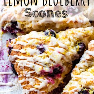 Baked slice of lemon blueberry scone with glaze on parchment paper. Text overlay reads " Lemon Blueberry Scones".