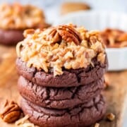 Stacked baked german chocolate cookies on wood board.