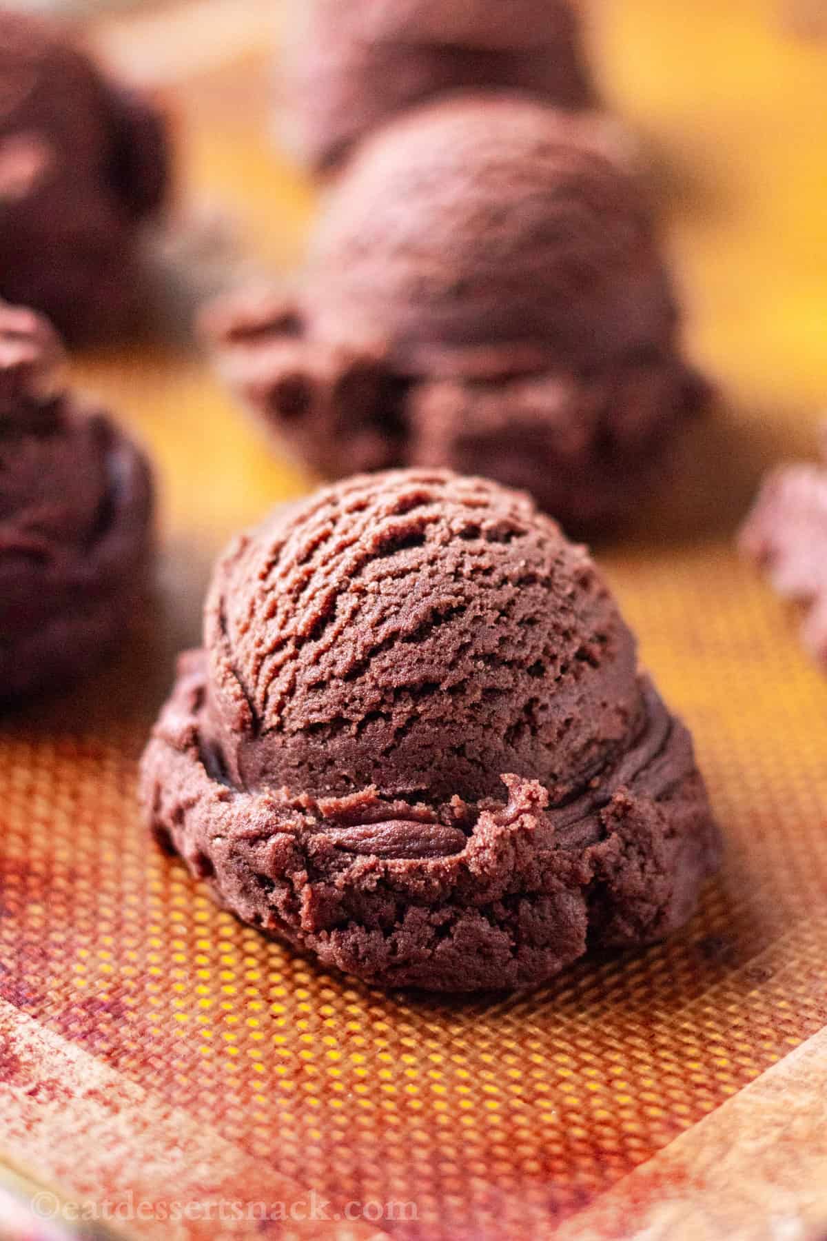 Raw chocolate cookie dough balls on baking sheet. 