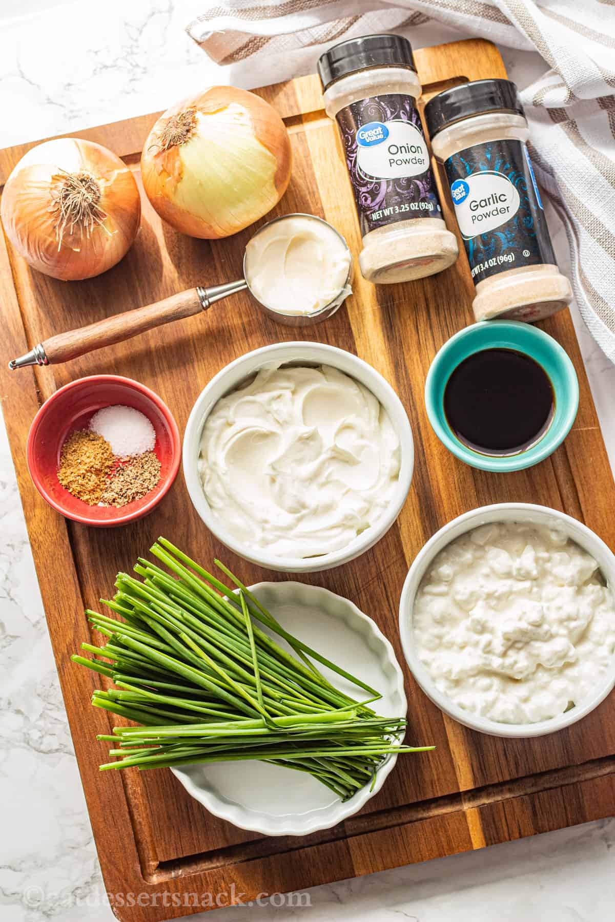 Ingredients for caramelized onion dip on wood cutting board. 
