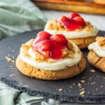 Baked cherry cheesecake cookie on black plate.