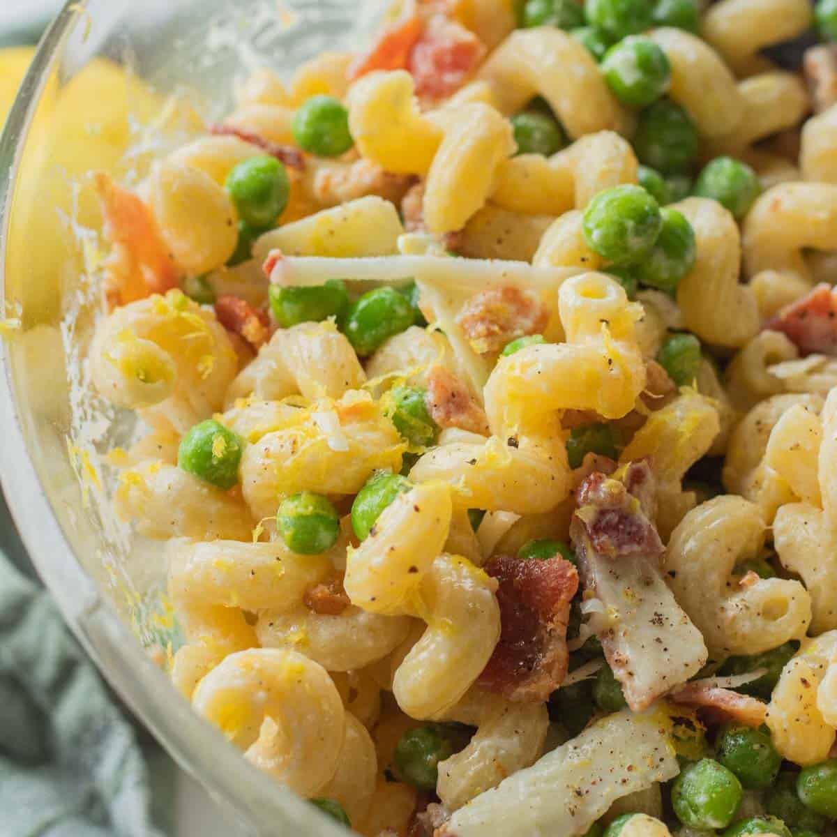 Lemon Pasta Salad with peas and bacon in clear bowl.