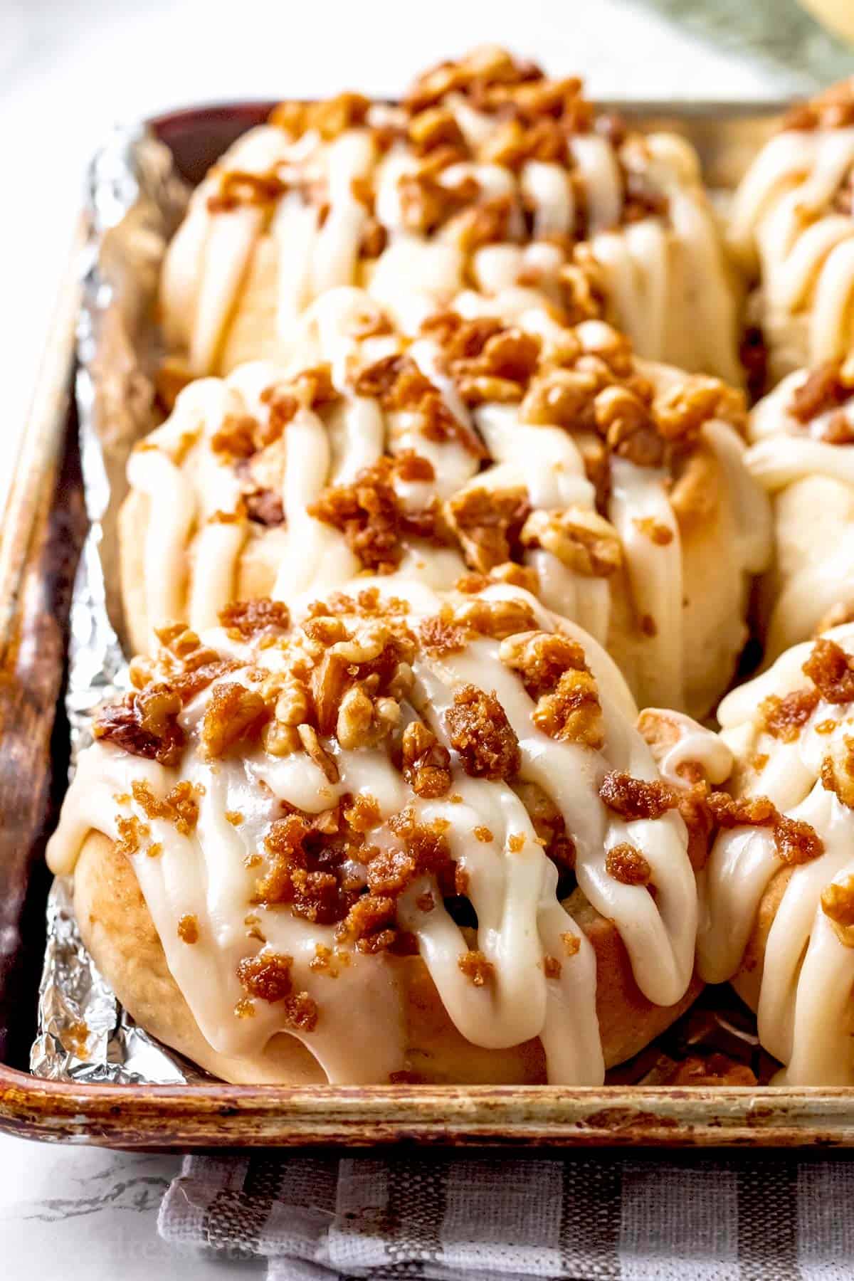 Baked and frosted banana cinnamon rolls in metal pan.