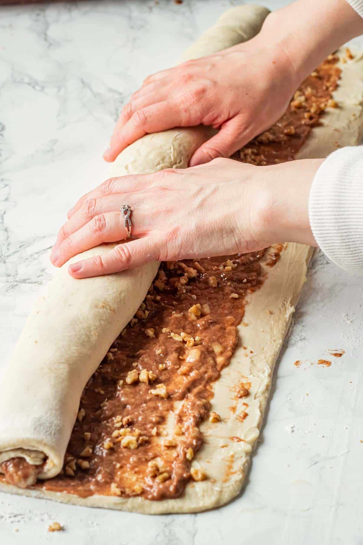 Rolling filling into raw banana cinnamon roll dough.