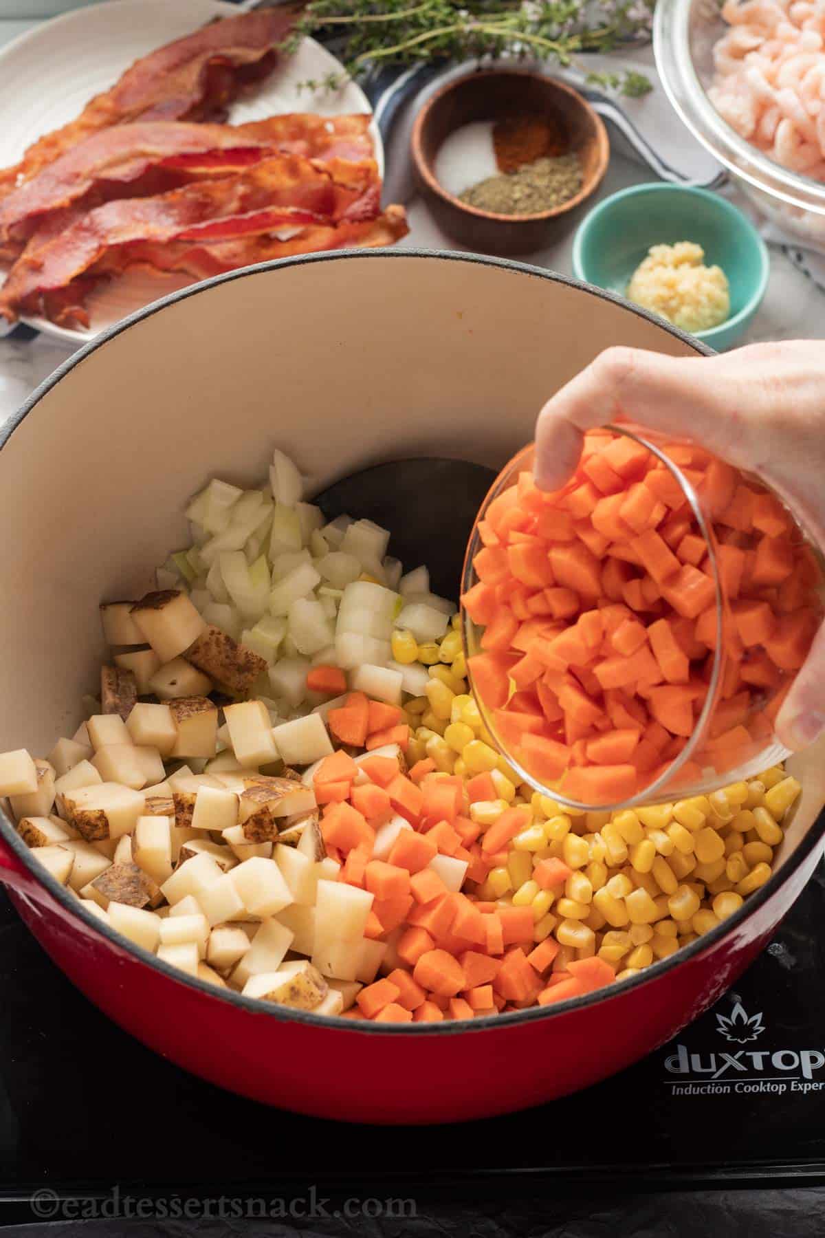 carrots, potatoes, corn and onions in cooking pot. 