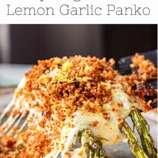 Cheesy baked asparagus on black spatula with gooey cheese.