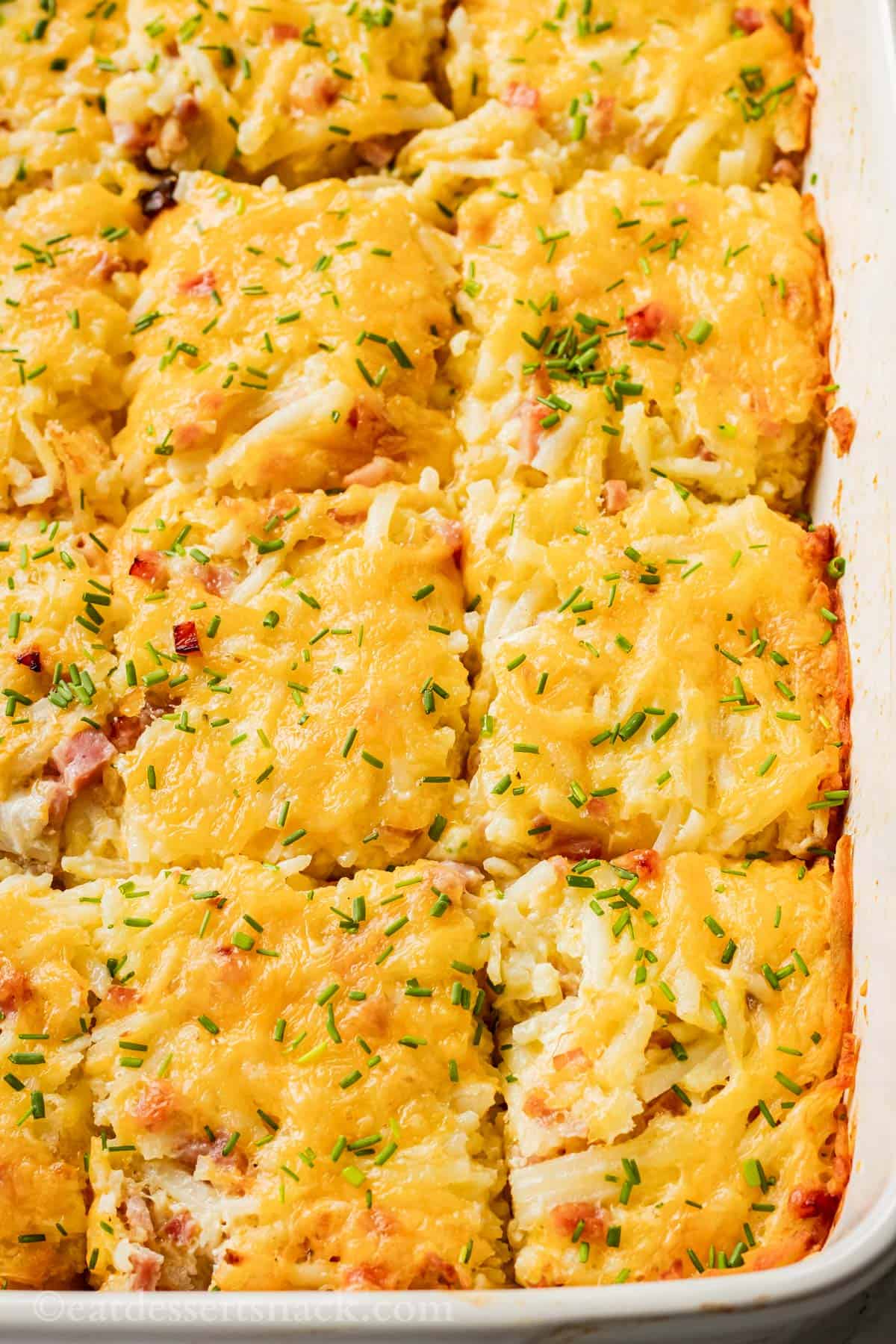 Sliced and baked ham and cheese casserole in white baking dish.