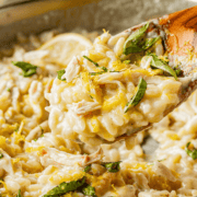 Wooden spoon of cooked orzo pasta with finished creamy lemon sauce.