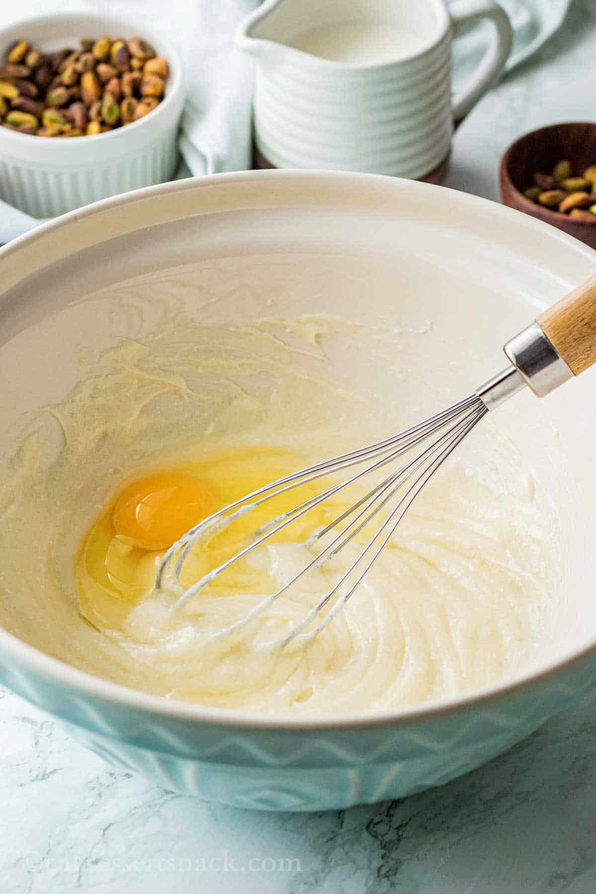 Whisk in blue bowl with egg, cream cheese, and sugar.