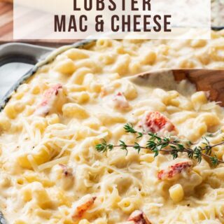 Gray frying pan of lobster mac and cheese on blue pot holder with cutting board and parmesan cheese on top.