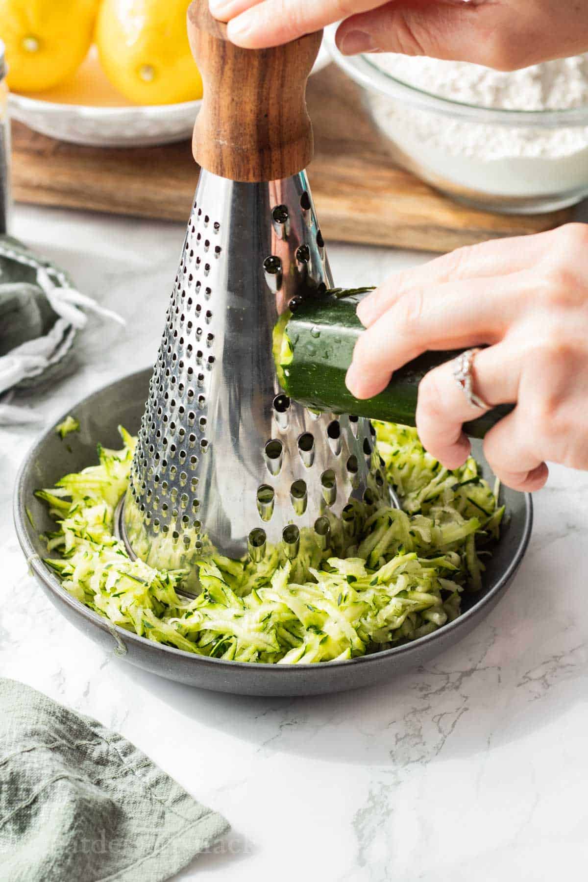 Hand grating zucchini into a plate.