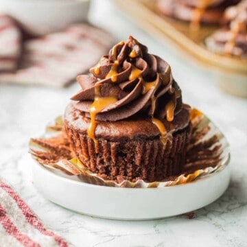 Unwrapped chocolate cupcake with frosting and caramel drizzle on top.
