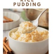 Spoonful of cooked eggnong rice pudding above white bowl full of pudding.