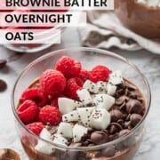 Bowl of brownie overnight oats with raspberries, chocolate chips, and cocnut.