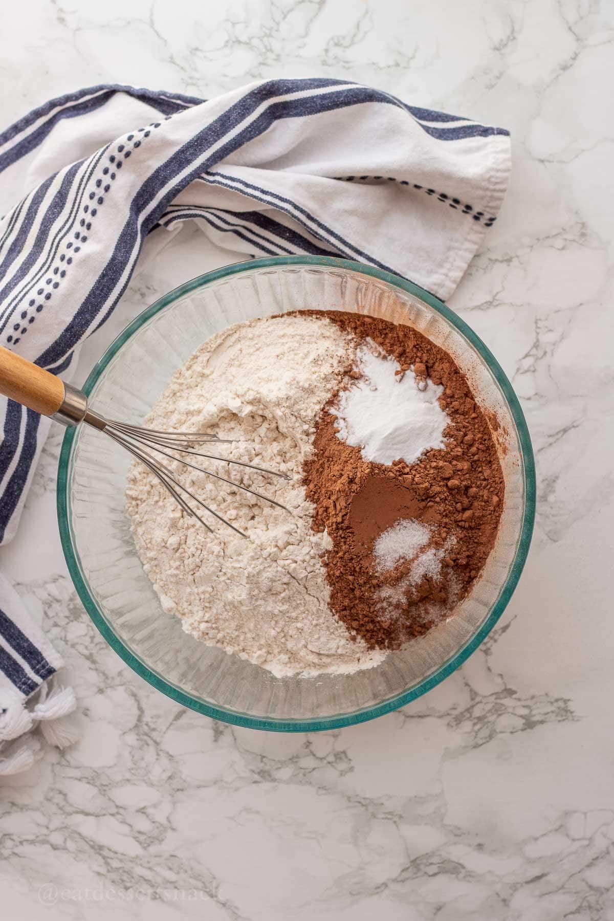 Flour, salt, baking soda, and cocoa powder in glass bowl with whisk.