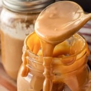 Spoonful of drizzling dulce de leche above glass jar.