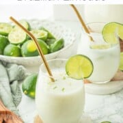 Brazilian limeade in glass cup with gold straw and lime slice on edge on marble coaster.