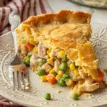 Slice of baked chicken pot pie on white plate with fork.