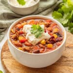 Cooked healthy taco soup in white bowl with sour cream and cilantro on top.