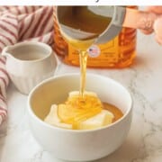 Pouring honey into white bowl of softened butter.