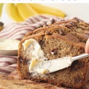 Knife spreading butter over sliced of baked sourdough discard banana bread.