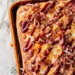 Baked BBQ chicken bacon ranch pizza in metal pan on marble countertop.