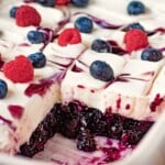 Blueberries and raspberries on whipped filling and sliced blueberry jello in white dish.
