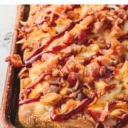 Baked BBQ chicken pizza in metal pan on marble counterop.