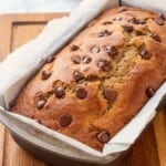 Baked sourdough banana bread in metal pan with chocolate chips on top.