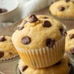 Tilted banana muffin in muffin wrapper on muffin tin.
