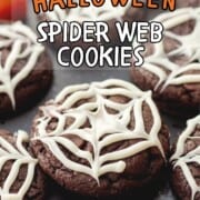 Baked chocolate spider web cookies on black plate.