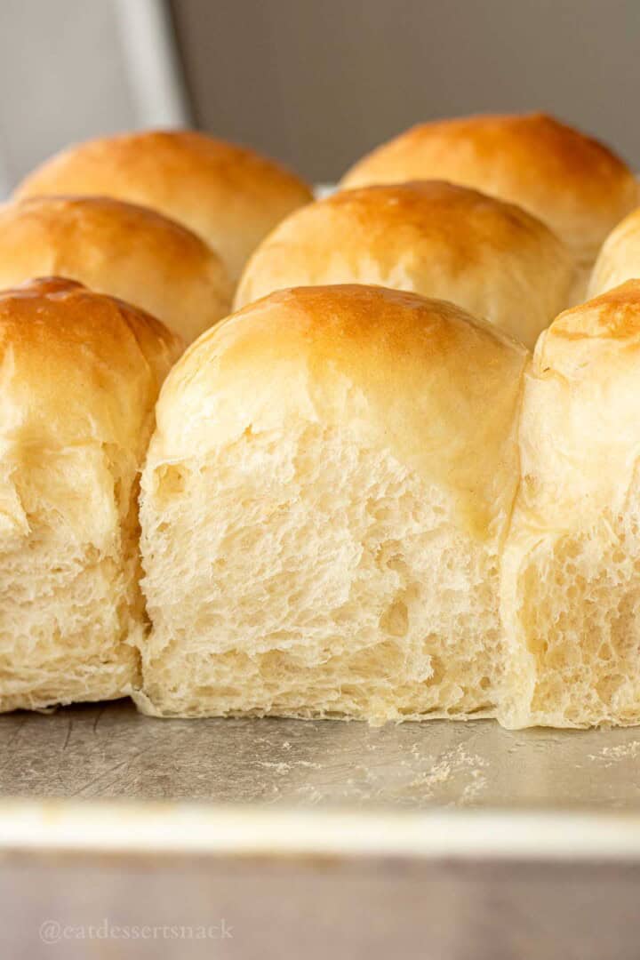 Baked soft fluffy dinner rolls in metal baking sheet.