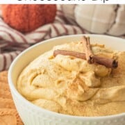 Bowl of pumpkin cream cheese dip in white bowl with cinnamon sticks.