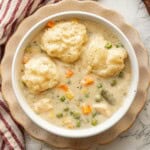 Cooked creamy chicken and dumpling soup in white bowl.
