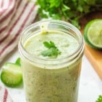Jar of blended avocado lime dressing with cilantro on top.