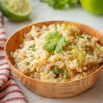 Cooked brown rice with lime zest and cilantro in wood bowl.