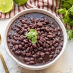 Cooked black beans with cilantro in white bowl.
