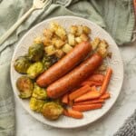 Cooked chicken sausage with veggies on white plate.