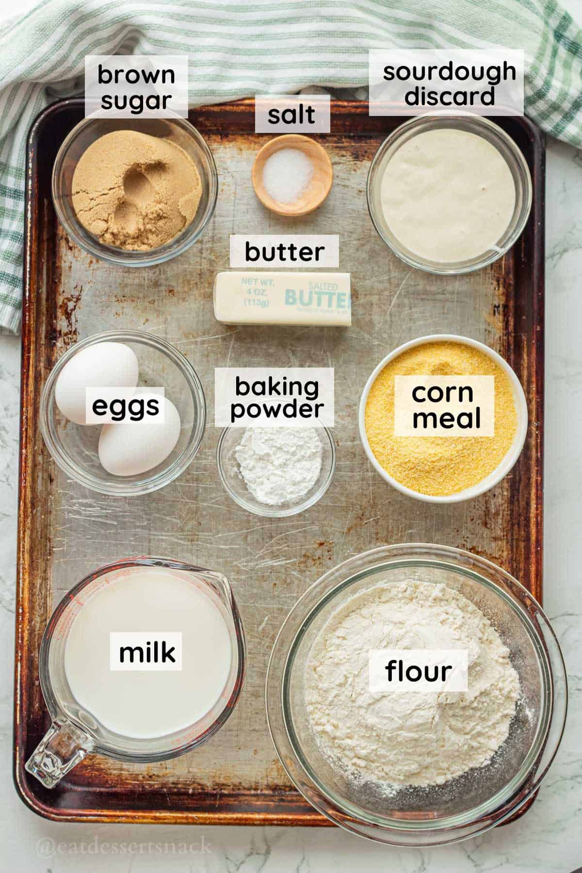 Labeled ingredients for sourdough discard cornbread on metal baking sheet in glass dishes.