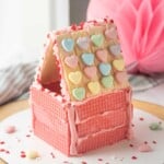 Pink wafer cookie house with hearts on roof.