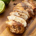 Cooked chicken sliced on wood cutting board.