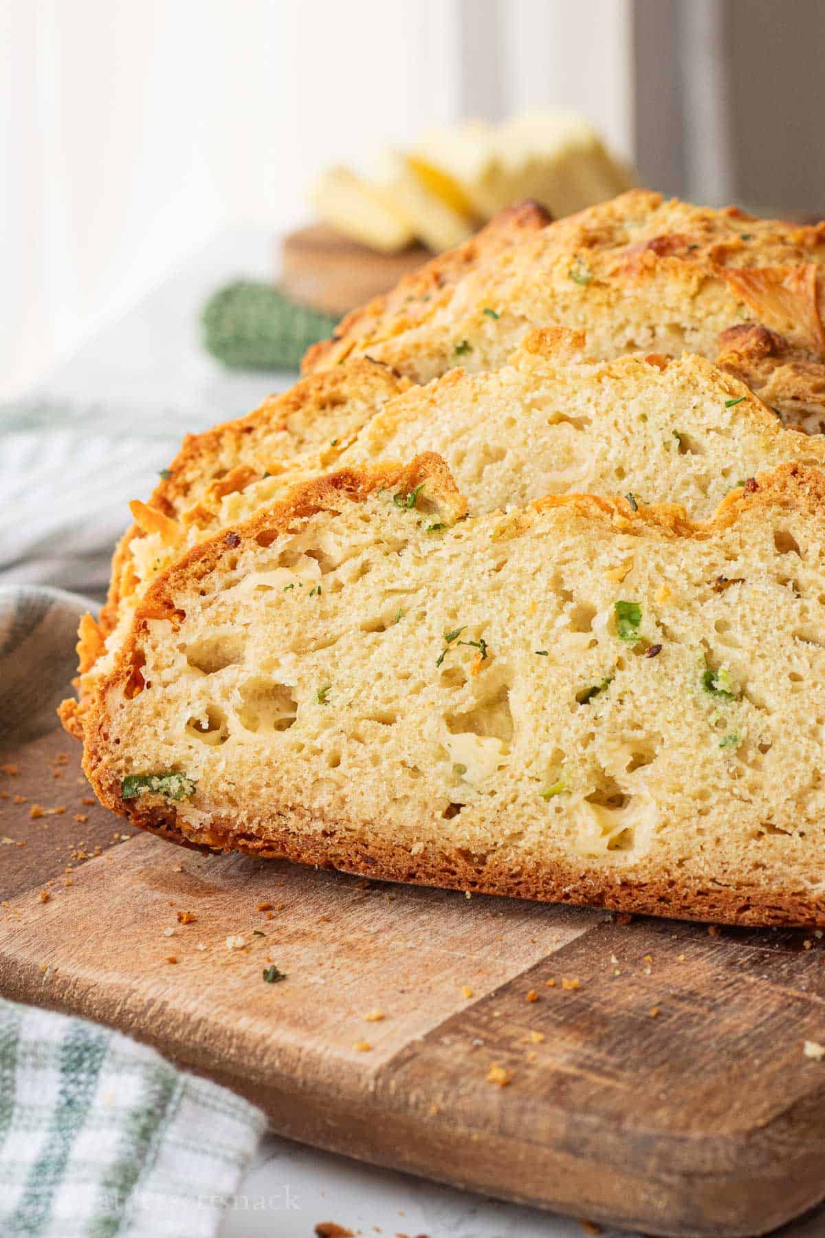 Sliced cheddar soda bread on wood cutting board.